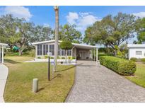 Charming home featuring a long drive and landscaped front yard, complemented by mature trees and a screened-in porch at 8517 Buckingham Pl, Palmetto, FL 34221