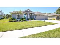 Charming home with arched windows, a bright blue door, and a well-manicured lawn at 8615 59Th E St, Parrish, FL 34219