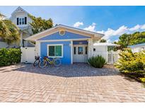 Charming blue bungalow featuring a brick driveway, white picket fence, and coastal-themed decor at 113 Palm Ave, Anna Maria, FL 34216