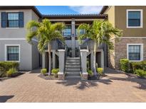 Beautiful condo exterior featuring a staircase entrance with tropical landscaping and brick paved parking at 12405 Osorio Ct # 202, Sarasota, FL 34238