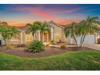 Beautiful home featuring a landscaped yard with palm trees and a well-maintained lawn at sunset at 1975 White Feather Ln, Nokomis, FL 34275