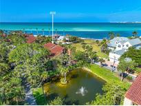 Beautiful aerial view of a coastal home with a pond and fountain in the front yard near a white sand beach at 212 Pass Key Rd # 212, Sarasota, FL 34242