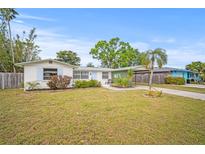 Charming single-story home with a well-maintained lawn, lush landscaping, and covered parking at 2620 White Sands Dr, Sarasota, FL 34231