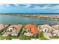 Stunning aerial view of waterfront homes with red tile roofs and lush landscaping overlooking a serene lake at 344 Maraviya Blvd, Nokomis, FL 34275