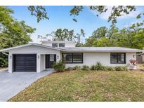 Charming single-story home with a modern garage door, landscaped yard, and a combination of light and dark exterior trim at 3857 Woodrow Ridge St, Sarasota, FL 34233