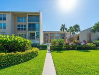 Beautiful condo complex with manicured lawn, lush landscaping and inviting walkway with partial ocean views at 845 Benjamin Franklin Dr # 104, Sarasota, FL 34236
