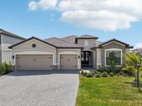 Beautiful single-story home featuring a three-car garage, well-manicured lawn, and stylish stone accents at 15104 Blue Bay Ter, Lakewood Ranch, FL 34211