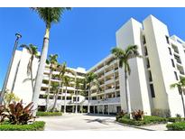 Beautiful building exterior with bright white facade, lush tropical landscaping, and paved driveway at 1932 Harbourside Dr # 217, Longboat Key, FL 34228