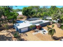 Modern home with a flat roof, solar panels, a front patio, and a well-manicured gravel yard at 448 58Th St, Sarasota, FL 34243