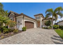 Charming single-Gathering home featuring a stone facade, a 2-car garage, and lush tropical landscaping at 5917 Cessna Run, Lakewood Ranch, FL 34211