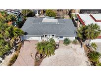 An aerial view of a single-story home featuring a new gray roof and tropical landscaping with palm trees at 711 Birdsong Ln, Sarasota, FL 34242