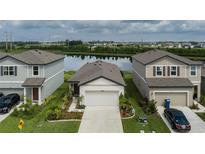 Inviting single-story home showcasing a well-manicured lawn and colorful flowerbeds, with a serene lake view beyond at 10459 Ladybug Cove, Parrish, FL 34219