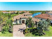 Elegant home featuring a tile roof, paver driveway, lush landscaping and waterfront views in a vibrant community at 13107 Bridgeport Xing, Lakewood Ranch, FL 34211