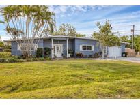 Charming single-story home with a well-maintained lawn, palm trees, and a light blue exterior at 1320 Magellan Dr, Sarasota, FL 34243