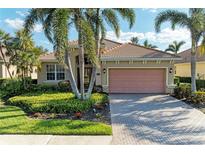 Charming single-story home featuring a tile roof, brick driveway, and tropical landscaping at 135 River Enclave Ct, Bradenton, FL 34212