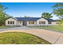 Charming one-story home boasts a white brick facade, black trim, and a spacious circular driveway at 1406 N Riverhills Dr, Temple Terrace, FL 33617