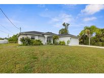 A well-kept single Gathering home showcases a green lawn and mature tropical landscaping at 2665 Chipley Ave, North Port, FL 34286