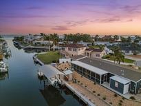 Waterfront home with boat dock, screened lanai, and manicured lawn at sunset at 303 Bryn Mawr Is, Bradenton, FL 34207