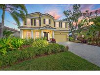 Two story home with yellow siding, brown shutters, manicured landscaping, and a paver driveway, perfect for curb appeal at 5522 Cartagena Dr, Sarasota, FL 34233
