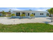 Charming single-story home featuring a white exterior, well-maintained lawn, and tropical landscaping at 6715 Georgia Ave, Bradenton, FL 34207