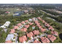 Scenic aerial view shows a neighborhood with red tile roofs near golf course and lake at 7340 Villa D Este Drive, Sarasota, FL 34238