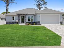 Charming single-story home with well-manicured lawn, stone accents, and a two-car garage at Lot 20 Garafola Ave, North Port, FL 34291