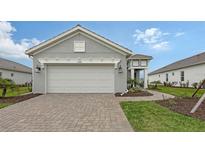 Home exterior showcasing a gray facade, two-car garage, and a brick-paved driveway at 12520 Brookgreen St, Venice, FL 34293