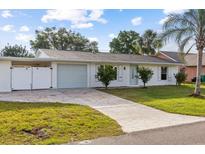 Charming single-story home featuring a well-manicured lawn, stone driveway, and attached garage with white picket fence at 2070 Carpetgreen St, Port Charlotte, FL 33948