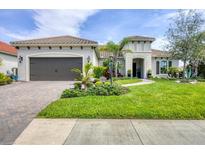 Beautiful single Gathering home with a two-car garage and meticulously landscaped yard on a sunny day at 27454 Hole In One Pl, Englewood, FL 34223