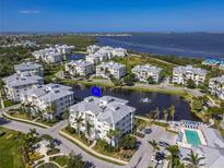 Beautiful aerial view of condo buildings with a sparkling pool, tranquil pond, and glimpses of the bay at 3420 77Th W St # 202, Bradenton, FL 34209