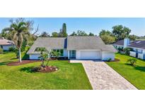 Charming single-story home boasting a manicured lawn, brick driveway, and tropical landscaping with mature palm trees at 3725 Spyglass Hill Rd, Sarasota, FL 34238