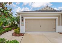 Attached one car garage of a well-maintained tan and white house with nicely manicured landscaping at 4021 Wildgrass Pl, Parrish, FL 34219