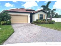 Charming single-story home with a brick driveway, two car garage, tile roof, and lush landscaping at 4406 Baltry Ct, Bradenton, FL 34211