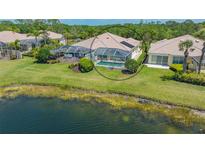 Backyard with screened-in pool overlooking the lake and lush green lawn, perfect for relaxing and entertaining at 7664 Camminare Dr, Sarasota, FL 34238