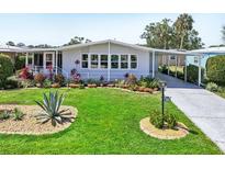 Charming single-story home featuring a lush lawn with tropical plants and a convenient covered carport at 8534 Imperial Cir, Palmetto, FL 34221