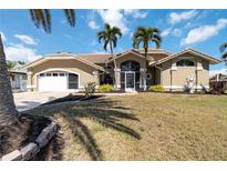 Charming single Gathering home features a well-maintained lawn and is enhanced with two palm trees at the front at 3069 Stone St, Port Charlotte, FL 33981