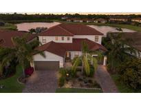 Expansive two-story home featuring a red tile roof, a three-car garage and lush tropical landscaping at 3814 Scrub Creek Run, Lakewood Ranch, FL 34211