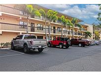Exterior shot of condos with parking lot with several parked vehicles on a sunny day with palm trees at 425 30Th W Ave # C208, Bradenton, FL 34205