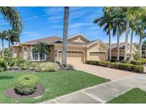 Stunning single-Gathering home with a three-car garage, paver driveway, lush landscaping, and soaring palm trees against a clear sky at 4250 Turnberry Cir, North Port, FL 34288