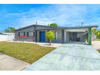 Charming single-story home featuring a blue door, fresh landscaping, and an attached carport, creating a welcoming curb appeal at 4409 Maceachen Blvd, Sarasota, FL 34233