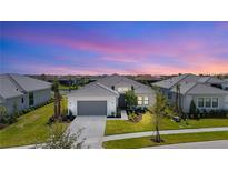 Beautiful one-story home with a gray roof, gray garage door, and tropical landscaping at sunset at 4711 Cedron Ct, Sarasota, FL 34240