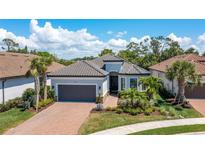 Beautiful single-story home with a tile roof, lush landscaping, a brick driveway, and an attached two-car garage at 5673 Piccolo St, Nokomis, FL 34275