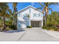 Charming coastal home with light blue shutters and lush tropical landscaping at 612 Fern St, Anna Maria, FL 34216