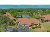 Stunning aerial view of a residential home with a terracotta roof next to a tranquil lake surrounded by lush greenery at 7269 Golf Pointe Way, Sarasota, FL 34243