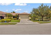 Inviting single-Gathering home featuring a tile roof, well-manicured lawn, and a two-car garage in a sunny, landscaped setting at 2064 Batello Dr, Venice, FL 34292