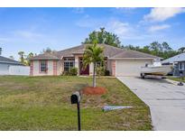 Charming single-story home with well-manicured lawn and a driveway with a boat parked on it at 2396 Malibu Ln, North Port, FL 34286