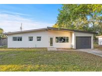 A charming, one-story home with a white exterior, gray trim and a well-manicured front lawn under a clear blue sky at 3169 Bellevue St, Sarasota, FL 34237