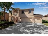 Two-story home featuring a three car garage, balcony, manicured lawn and lush landscaping at 4007 61St E Dr, Bradenton, FL 34203