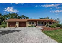 Charming single-story home with a spacious driveway, attached garage, and inviting front porch with garden at 60 Liles St, Terra Ceia, FL 34250