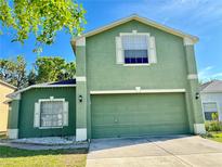 Two-story green home featuring an attached two-car garage and well-maintained landscaping at 7114 Hamilton Park Blvd, Tampa, FL 33615